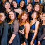 A group of people dressed in formal black attire pose together for a group photo.