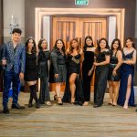 A group of people dressed in formal attire posing together indoors.