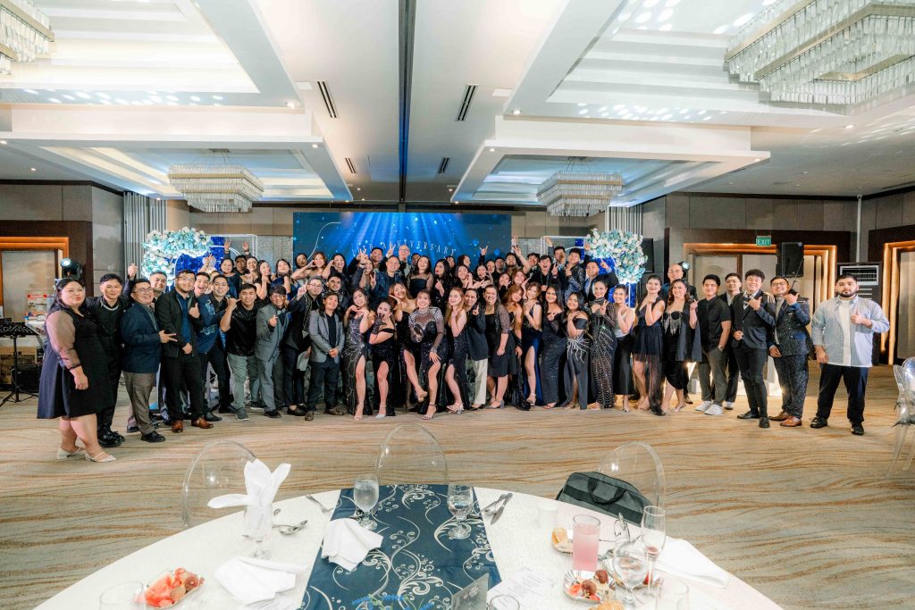 Large group of people dressed formally posing together in a decorated banquet hall.