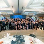 Large group of people dressed formally posing together in a decorated banquet hall.