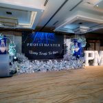 Stage setup for a Profitmaster event with floral decorations and large illuminated PM11 letters.