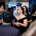 People in formal attire converse at a crowded indoor event or party.