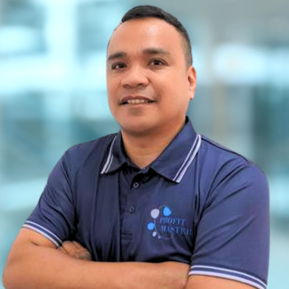 Man in a navy blue collared shirt stands with arms crossed against a blurred background.